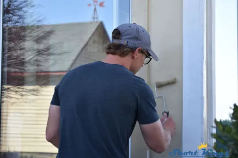 Applying white paint to new window trim with a roller